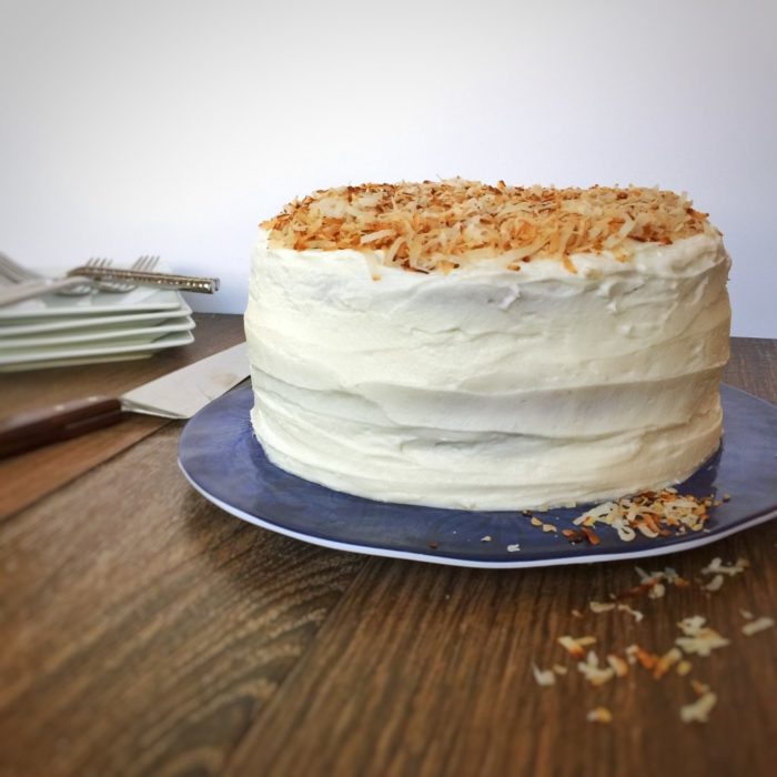 cake with coconut frosting and toasted coconut shavings on top